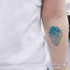 手臂上带有几何元素的蓝色山纹身图案