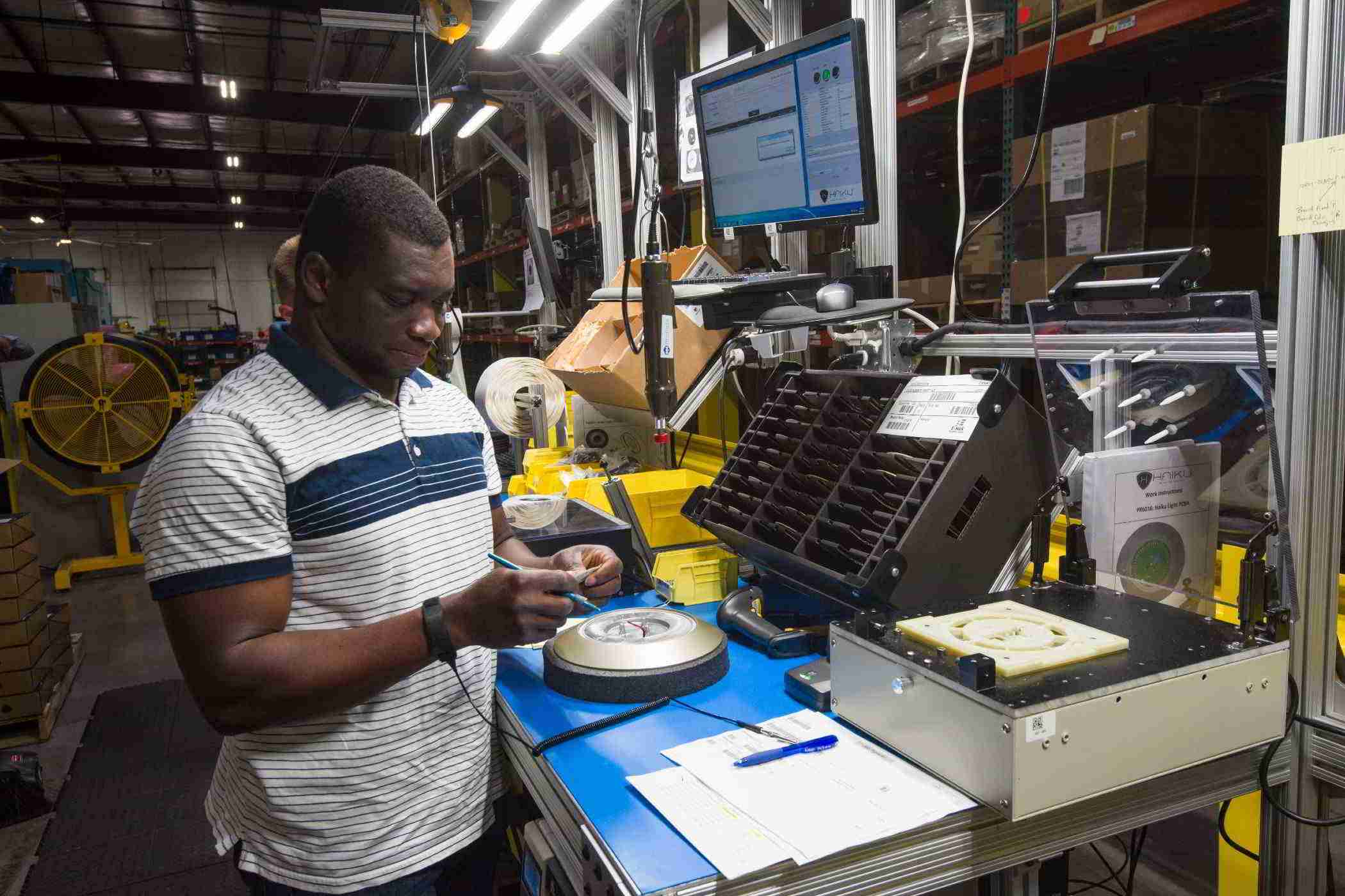 Young man on a manufacturing floor reading a label